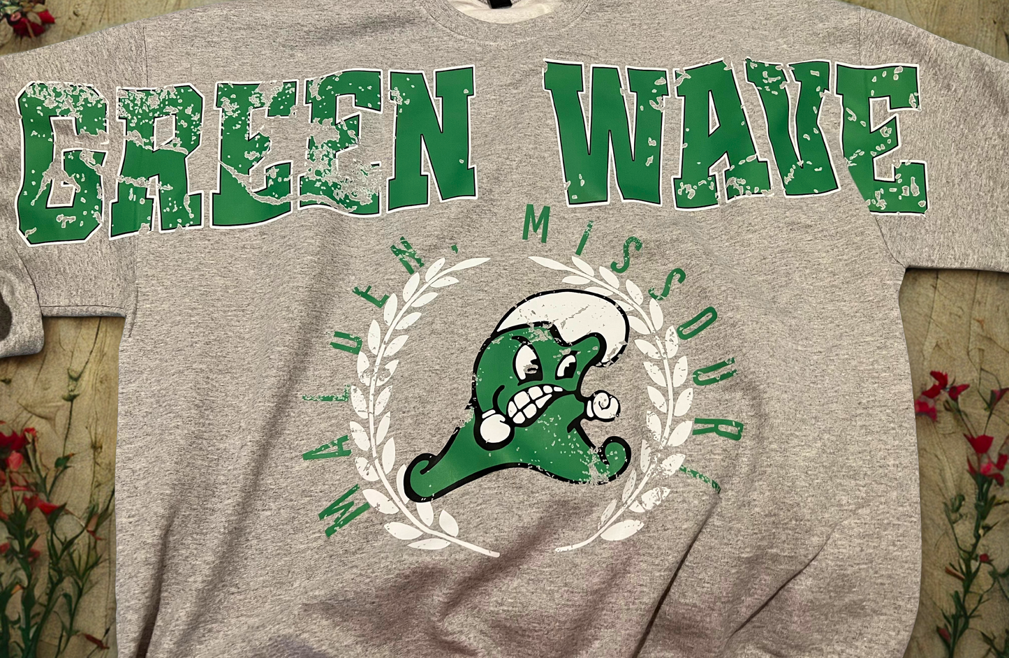Gray t-shirt with 'Green Wave' text and logo on a floral background