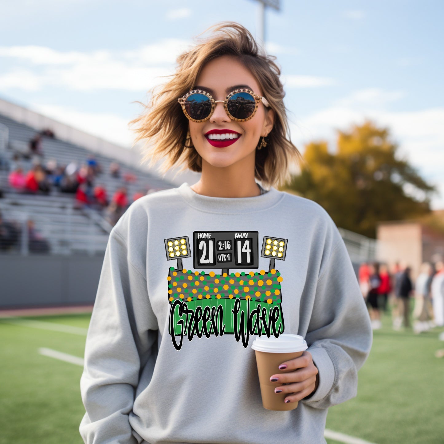 Woman wearing a sweatshirt with 'Green Wave' design on a sports field